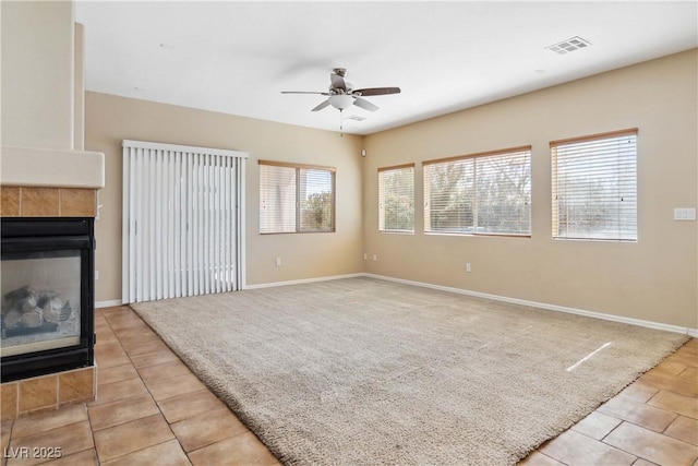 unfurnished living room with visible vents, light carpet, a ceiling fan, and a fireplace