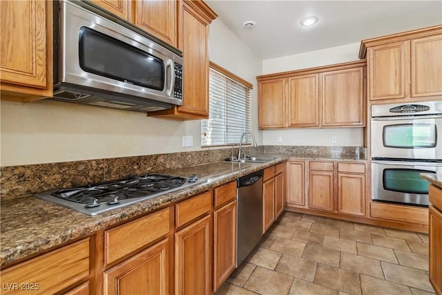 kitchen with recessed lighting, appliances with stainless steel finishes, dark stone counters, and a sink