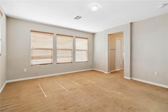 empty room featuring visible vents, light colored carpet, and baseboards