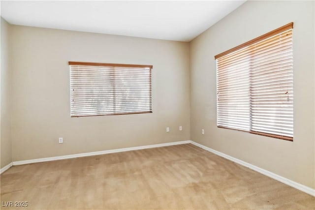 spare room with baseboards and light carpet