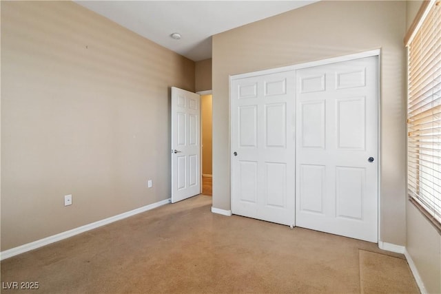 unfurnished bedroom featuring light colored carpet, a closet, and baseboards