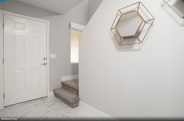 interior space featuring marble finish floor, stairway, and baseboards