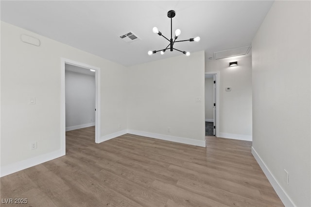 unfurnished room featuring light wood finished floors, baseboards, visible vents, and a chandelier