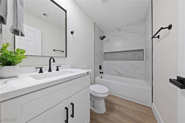 bathroom with toilet, wood finished floors, vanity, visible vents, and tub / shower combination