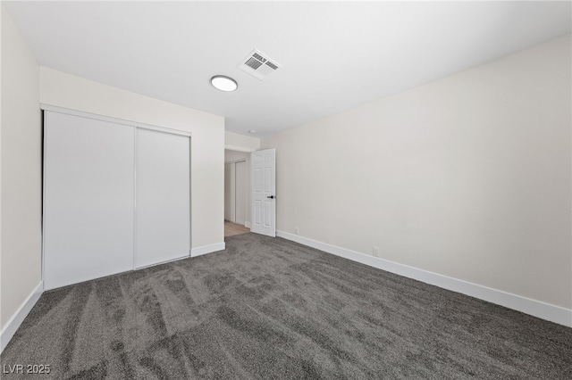 unfurnished bedroom with a closet, carpet, visible vents, and baseboards