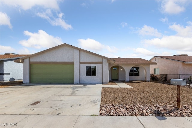 view of front of property featuring a garage, concrete driveway, fence, and stucco siding