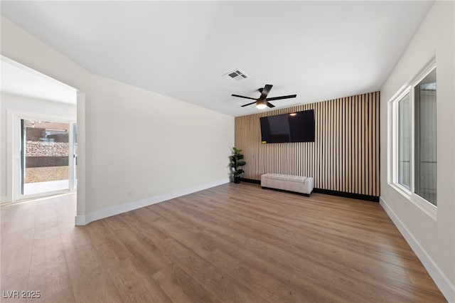 unfurnished room featuring ceiling fan, wood finished floors, visible vents, and baseboards