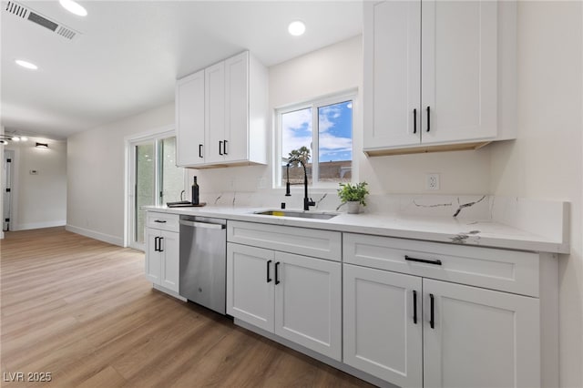 kitchen with visible vents, white cabinets, light wood-style flooring, stainless steel dishwasher, and a sink