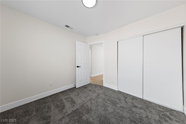 unfurnished bedroom with carpet floors, baseboards, visible vents, and a closet