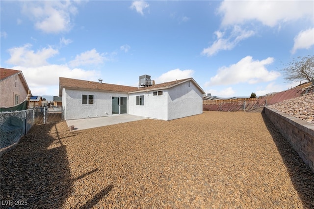 back of property with stucco siding, a fenced backyard, central AC unit, and a patio