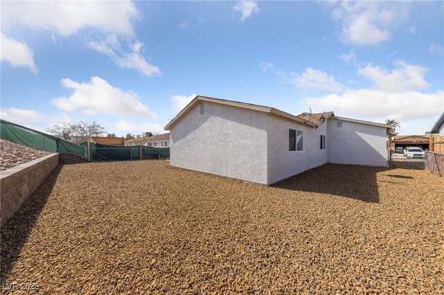 rear view of property with a fenced backyard and stucco siding