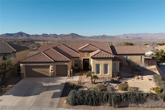 mediterranean / spanish-style house with a mountain view, driveway, an attached garage, and stucco siding