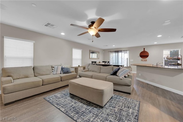 living room featuring recessed lighting, wood finished floors, visible vents, and baseboards