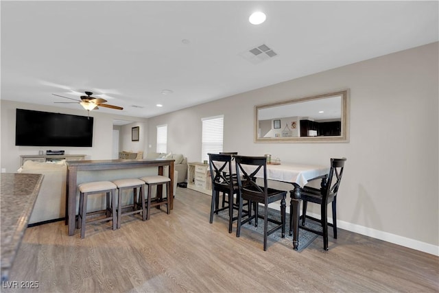 dining room with visible vents, ceiling fan, light wood-style flooring, and baseboards