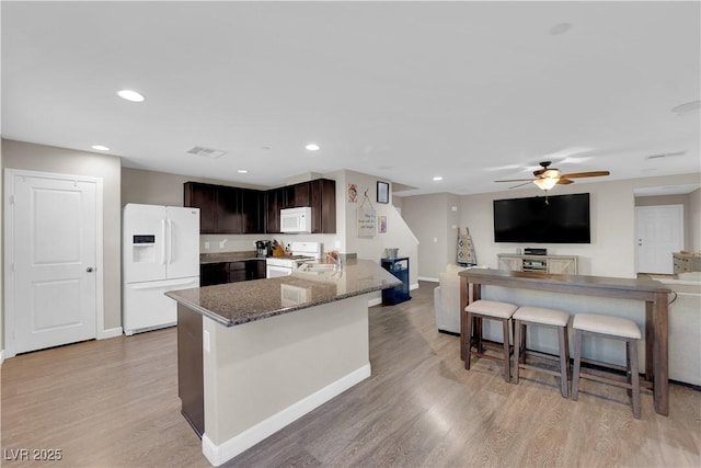 kitchen featuring light wood-type flooring, white appliances, visible vents, and a sink