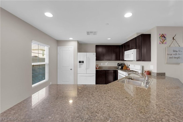 kitchen with dark brown cabinetry, white appliances, visible vents, and recessed lighting