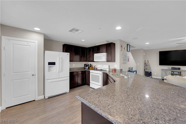 kitchen with light wood-style flooring, white appliances, a sink, visible vents, and open floor plan