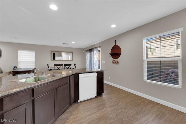 kitchen with baseboards, dishwasher, light wood-type flooring, a sink, and recessed lighting