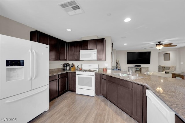 kitchen with visible vents, light wood-style flooring, a sink, light stone countertops, and white appliances