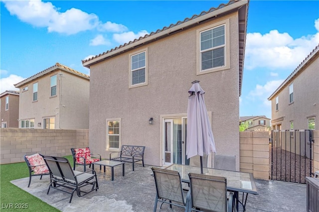 rear view of property featuring a patio area, fence, a tile roof, and stucco siding