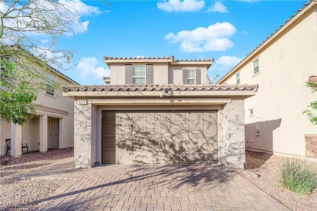 mediterranean / spanish home with a tiled roof, decorative driveway, and stucco siding