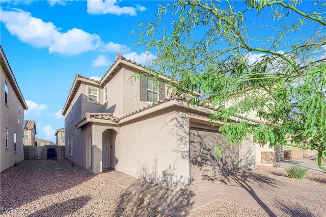 view of front of property with stucco siding, fence, and a tiled roof