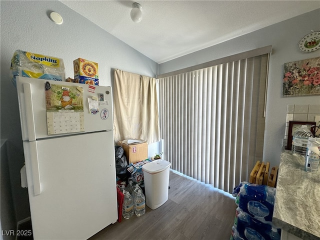 interior space with freestanding refrigerator, vaulted ceiling, and wood finished floors