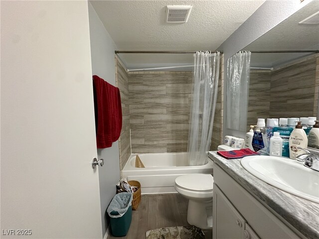 full bath with visible vents, shower / tub combo with curtain, wood finished floors, a textured ceiling, and vanity