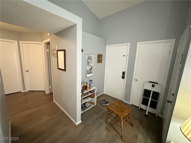 corridor featuring a textured ceiling, baseboards, and wood finished floors