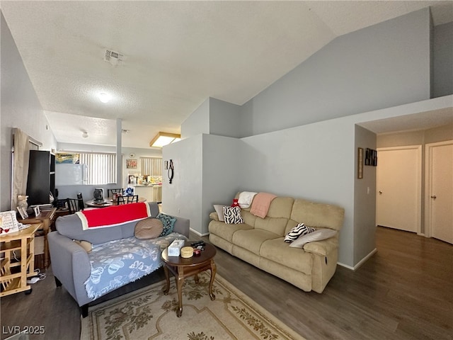 living room featuring visible vents, vaulted ceiling, baseboards, and wood finished floors