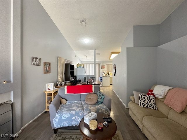 living area with baseboards, a textured ceiling, visible vents, and wood finished floors