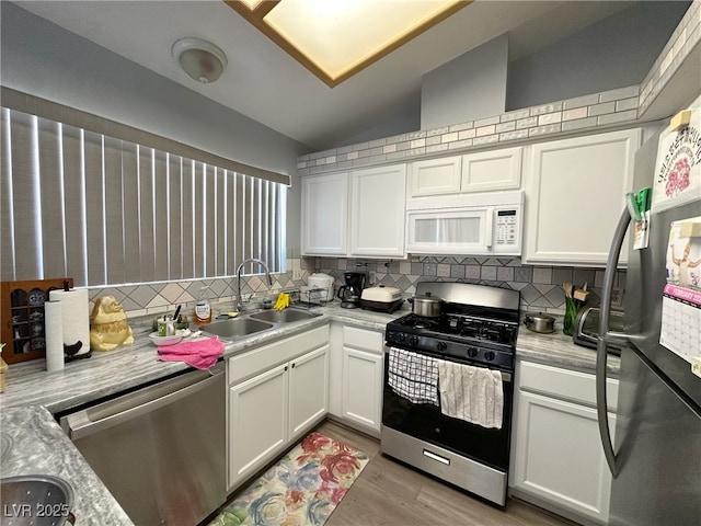 kitchen featuring a sink, white cabinetry, light countertops, appliances with stainless steel finishes, and tasteful backsplash