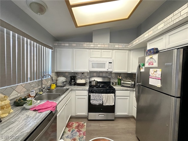 kitchen with stainless steel appliances, white cabinetry, and decorative backsplash