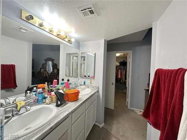 bathroom with visible vents, a sink, a textured ceiling, and double vanity