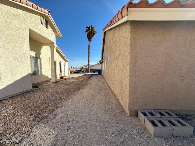 view of side of home with a tiled roof and stucco siding