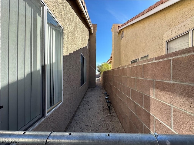 view of side of property with fence and stucco siding