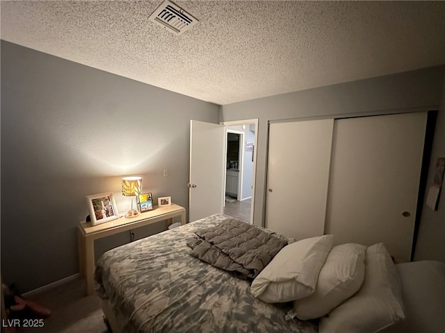 bedroom featuring a textured ceiling, visible vents, and a closet