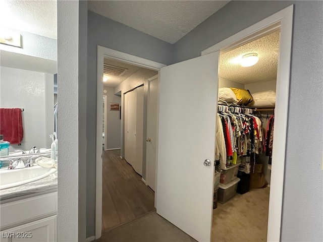 hall featuring a textured ceiling and a sink