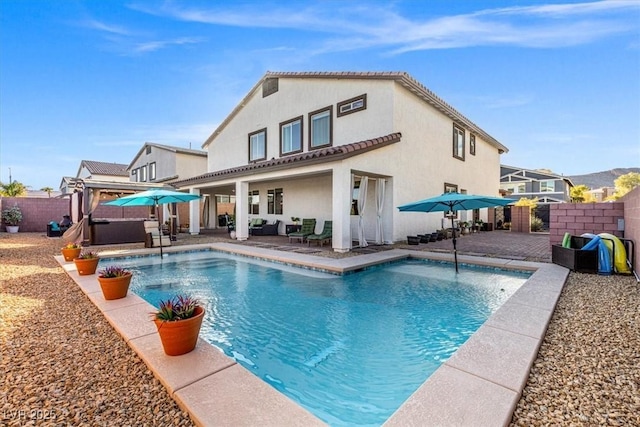 rear view of house with a patio, a fenced backyard, a fenced in pool, and stucco siding