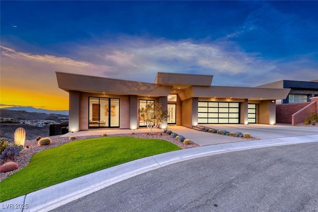 contemporary home with a garage, concrete driveway, a front yard, and stucco siding