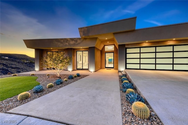 modern home with driveway, an attached garage, and stucco siding