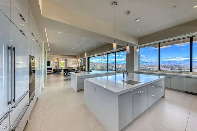 kitchen featuring a sink, open floor plan, gray cabinets, modern cabinets, and a large island with sink