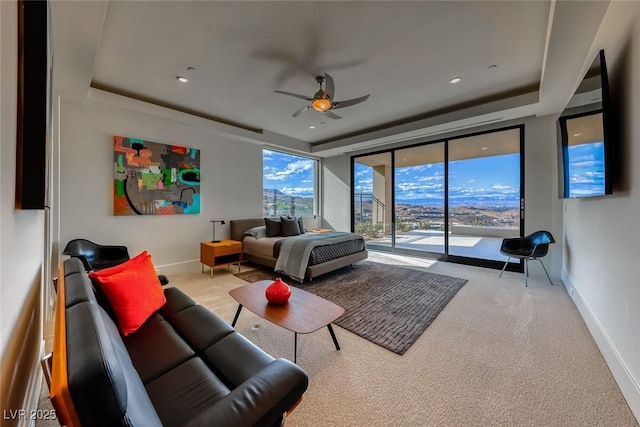 carpeted bedroom featuring access to exterior, a tray ceiling, and baseboards