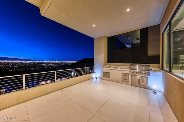 patio at twilight featuring an outdoor kitchen, a balcony, grilling area, a mountain view, and a sink