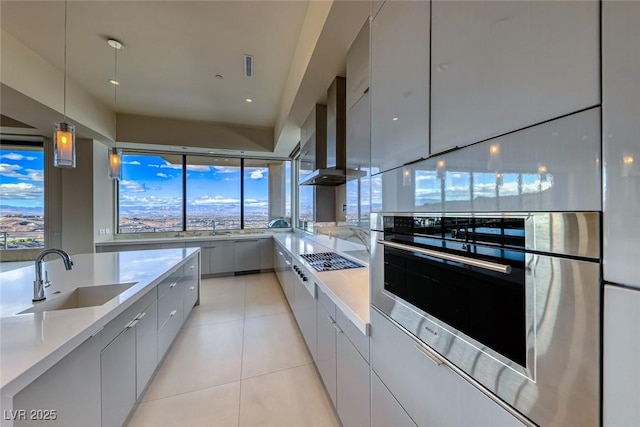 kitchen with light tile patterned floors, light countertops, a sink, modern cabinets, and wall chimney exhaust hood