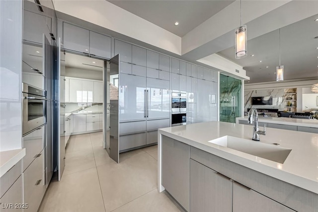 kitchen with light tile patterned floors, open floor plan, gray cabinets, stainless steel oven, and a sink