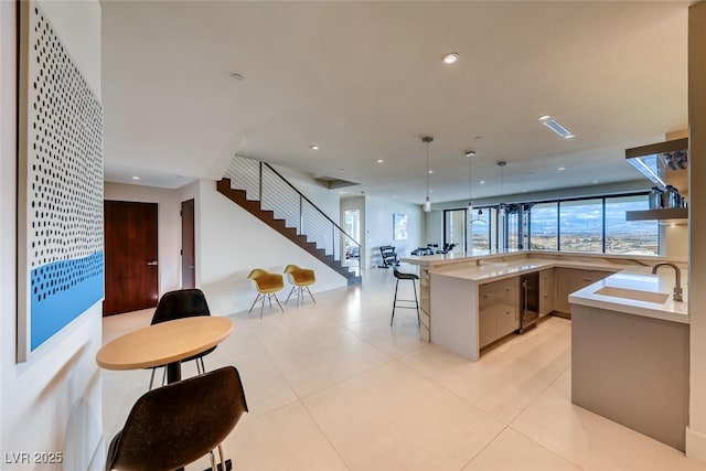 kitchen with wine cooler, open floor plan, light countertops, a kitchen bar, and a sink