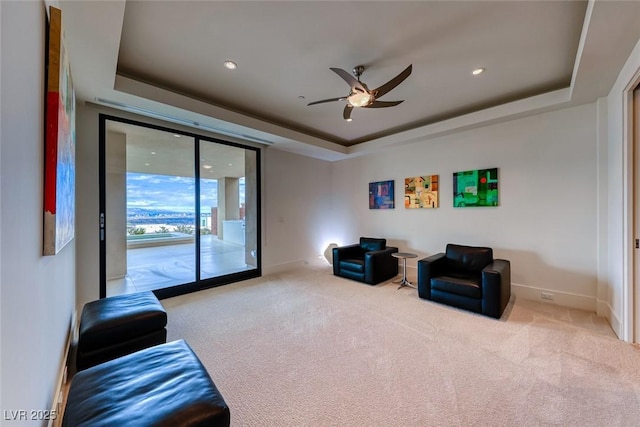 sitting room featuring baseboards, a ceiling fan, a tray ceiling, carpet flooring, and recessed lighting