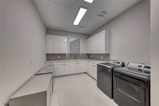 laundry room featuring light tile patterned flooring, a sink, visible vents, cabinet space, and washing machine and clothes dryer