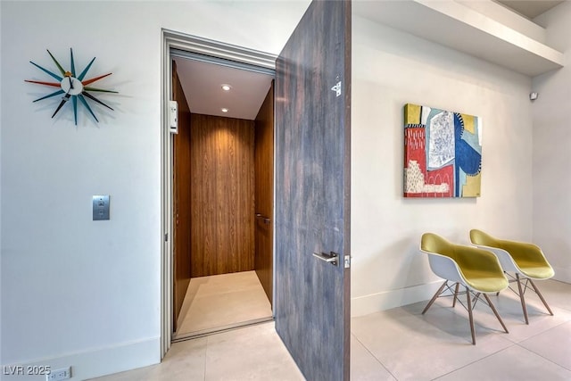 interior space with tile patterned flooring, elevator, and baseboards